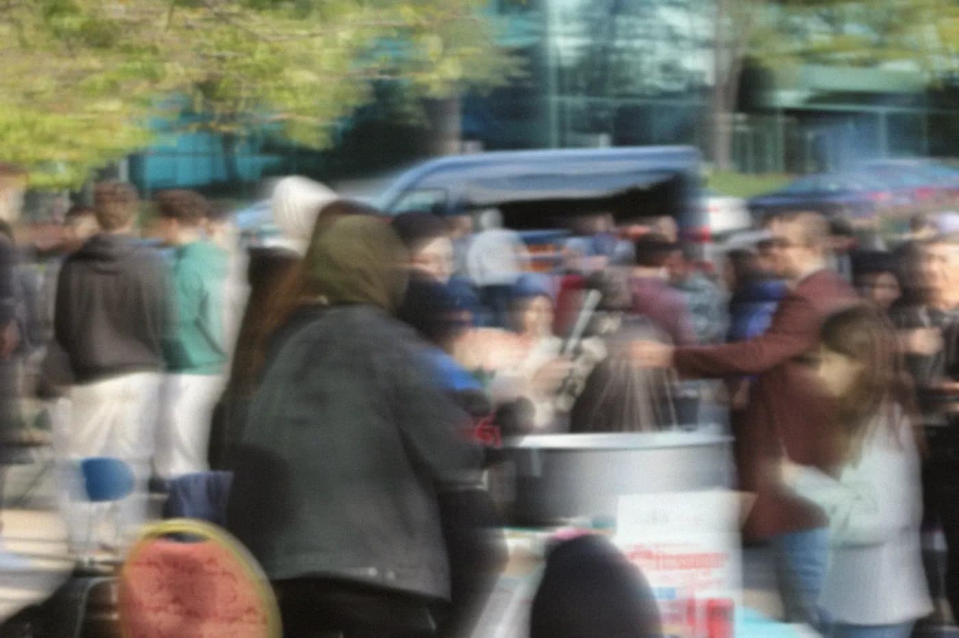 A crowd of students and families around a stand at a LeadUp community fundraiser, blurred with motion.
