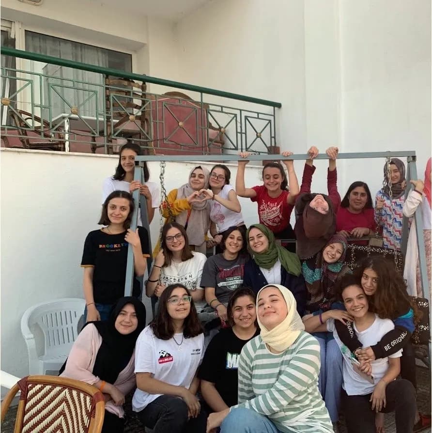 A group of smiling girls pose on a balcony at the camp in Greece.