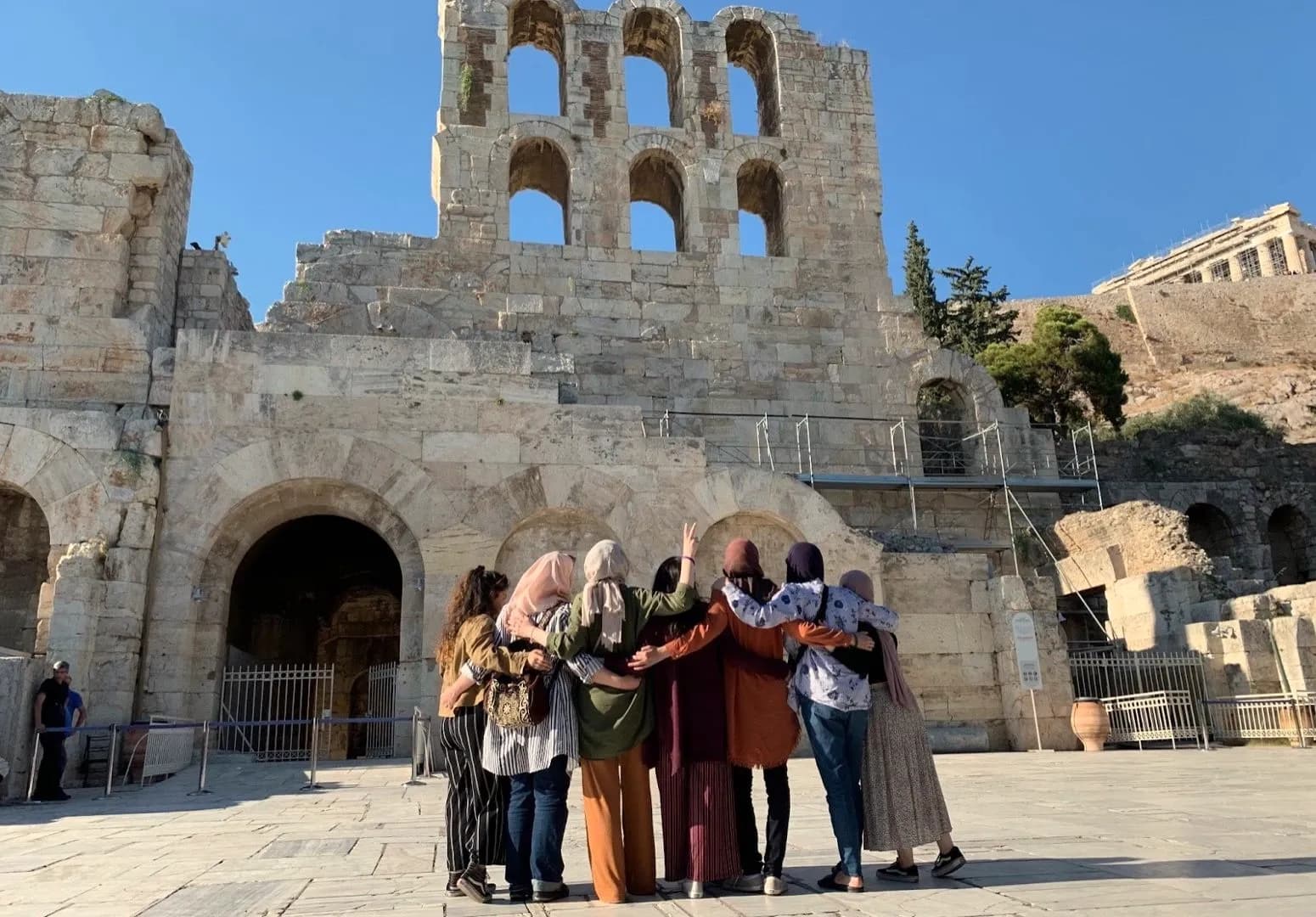 LeadUp mentors with their arms around each other in front of the Odeon of Herodes Atticus in Athens.