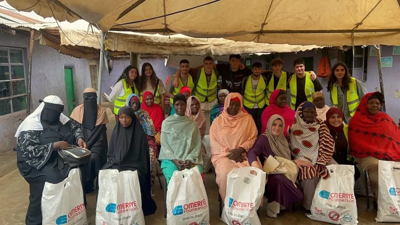 Volunteers stand behind women from the village who hold gift bags of household supplies.